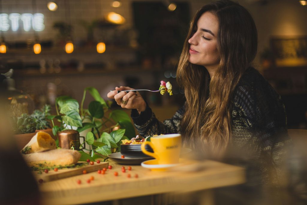 Woman thoughtfully eating a meal alone at a café table